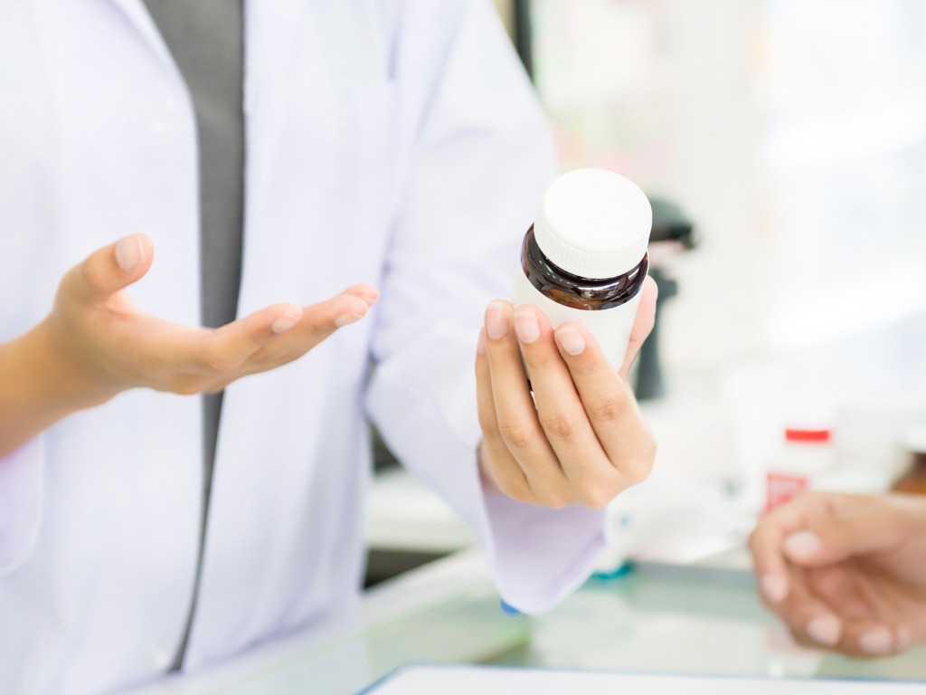 female-pharmacist-holding-medicine-bottle-giving-advice-to-customer-picture-id876037360 female-pharmacist-holding-medicine-bottle-giving-advice-to-customer-picture-id876037360