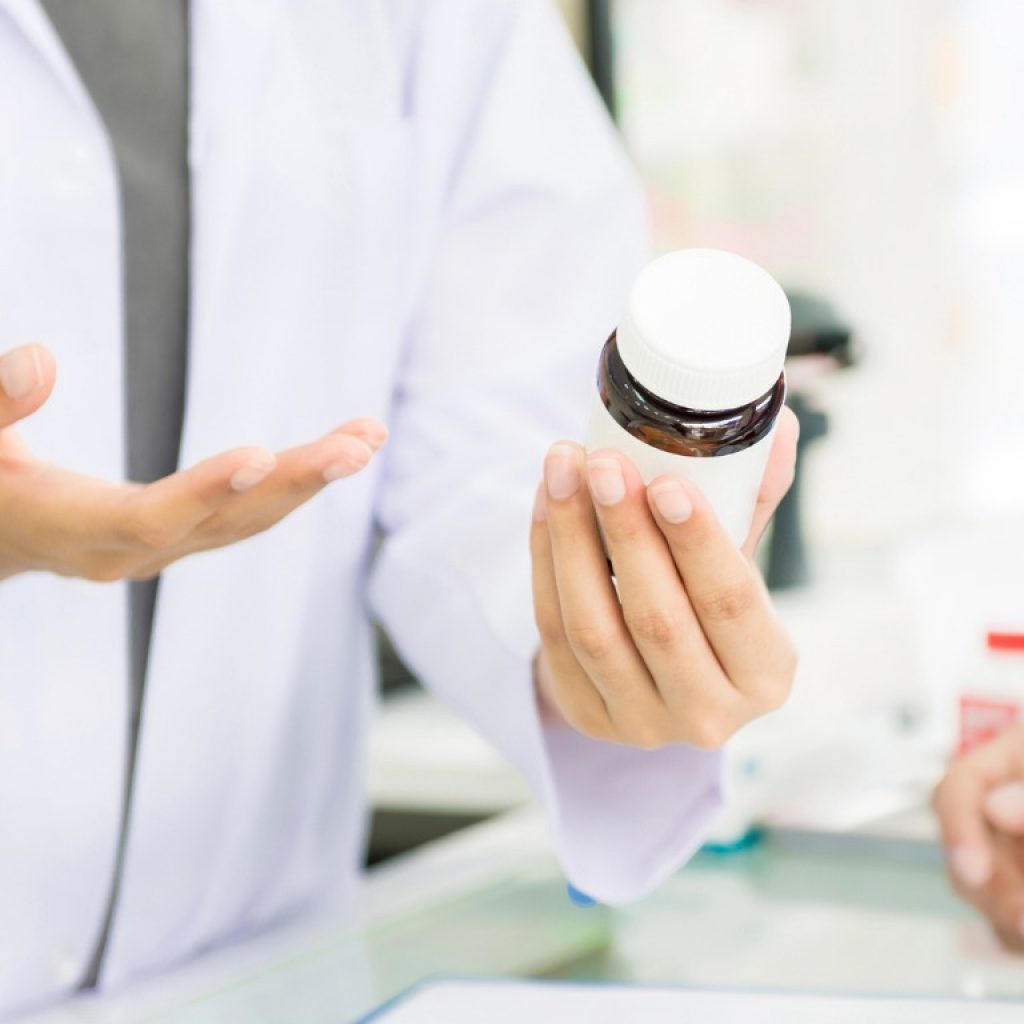 female-pharmacist-holding-medicine-bottle-giving-advice-to-customer-picture-id876037360 female-pharmacist-holding-medicine-bottle-giving-advice-to-customer-picture-id876037360