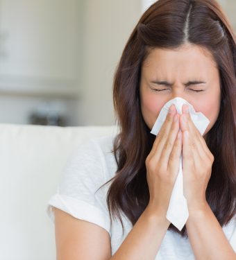 Brunette sneezing in a tissue Brunette sneezing in a tissue in the living room